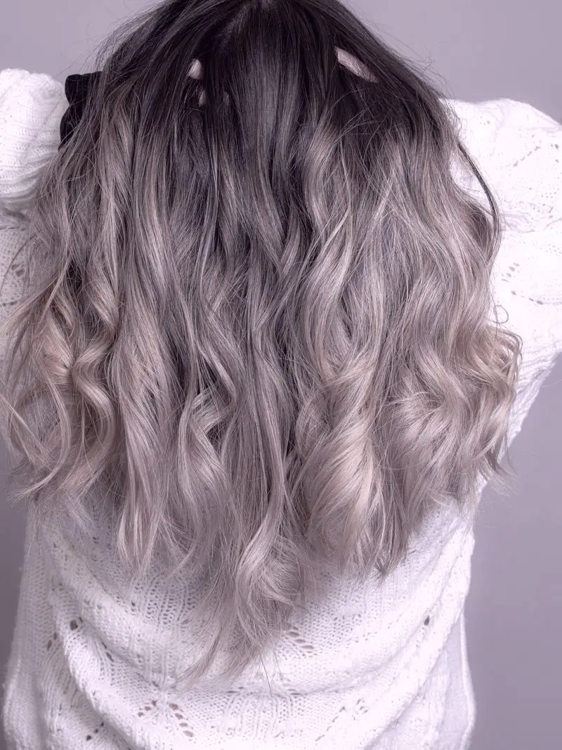 Long hair worn down, dark at the root and soft ash through the lengths