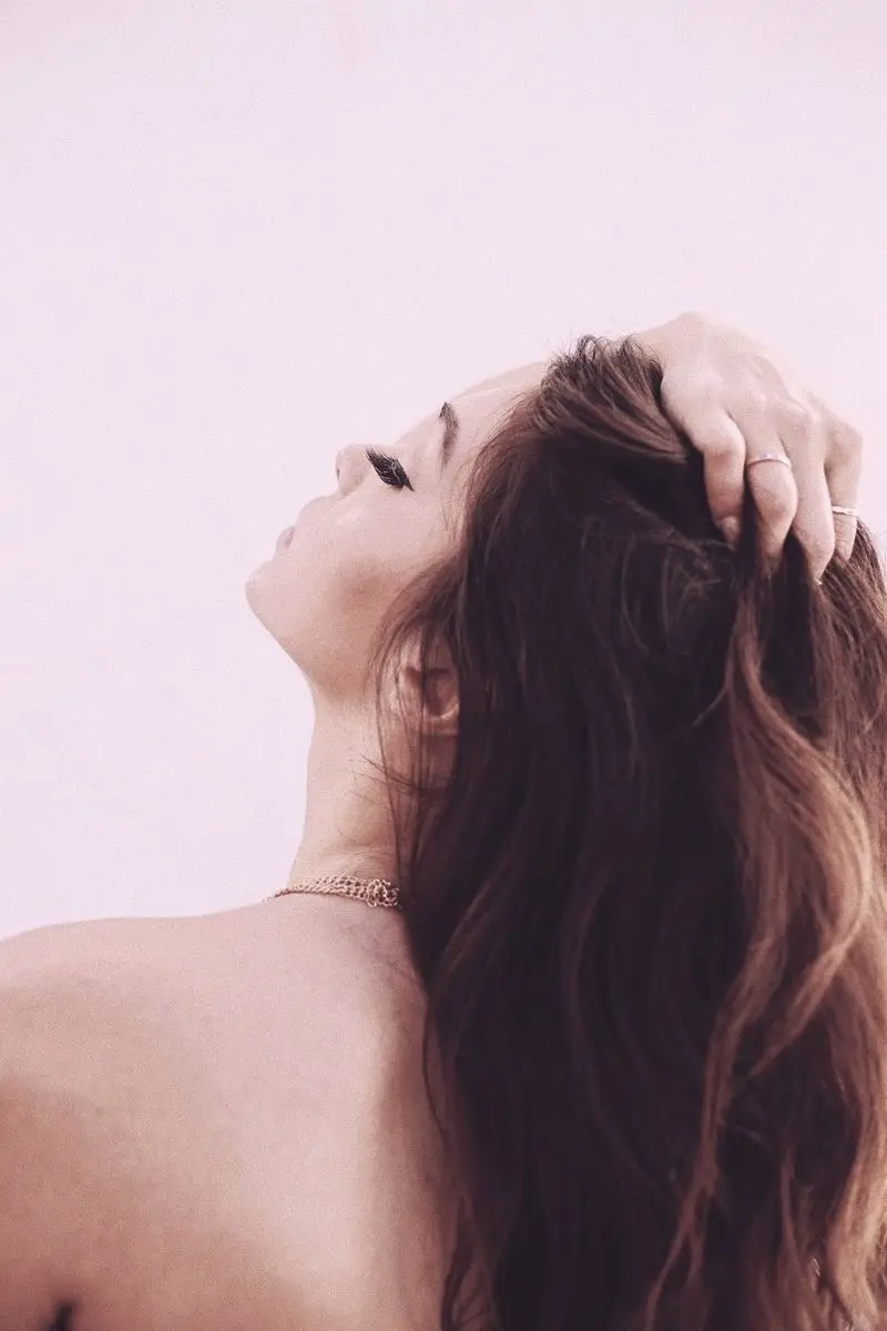 Long red hair held back from the face with both hands