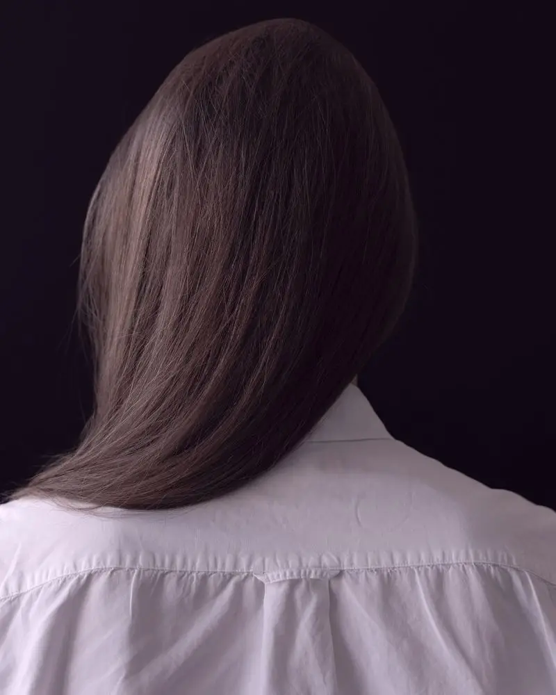 A blunt brunette length seen from behind against a dark ground